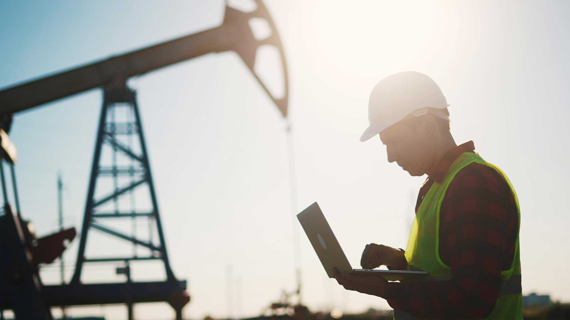 oil-business.-a-worker-works-next-to-an-oil-pump-holding-a-laptop