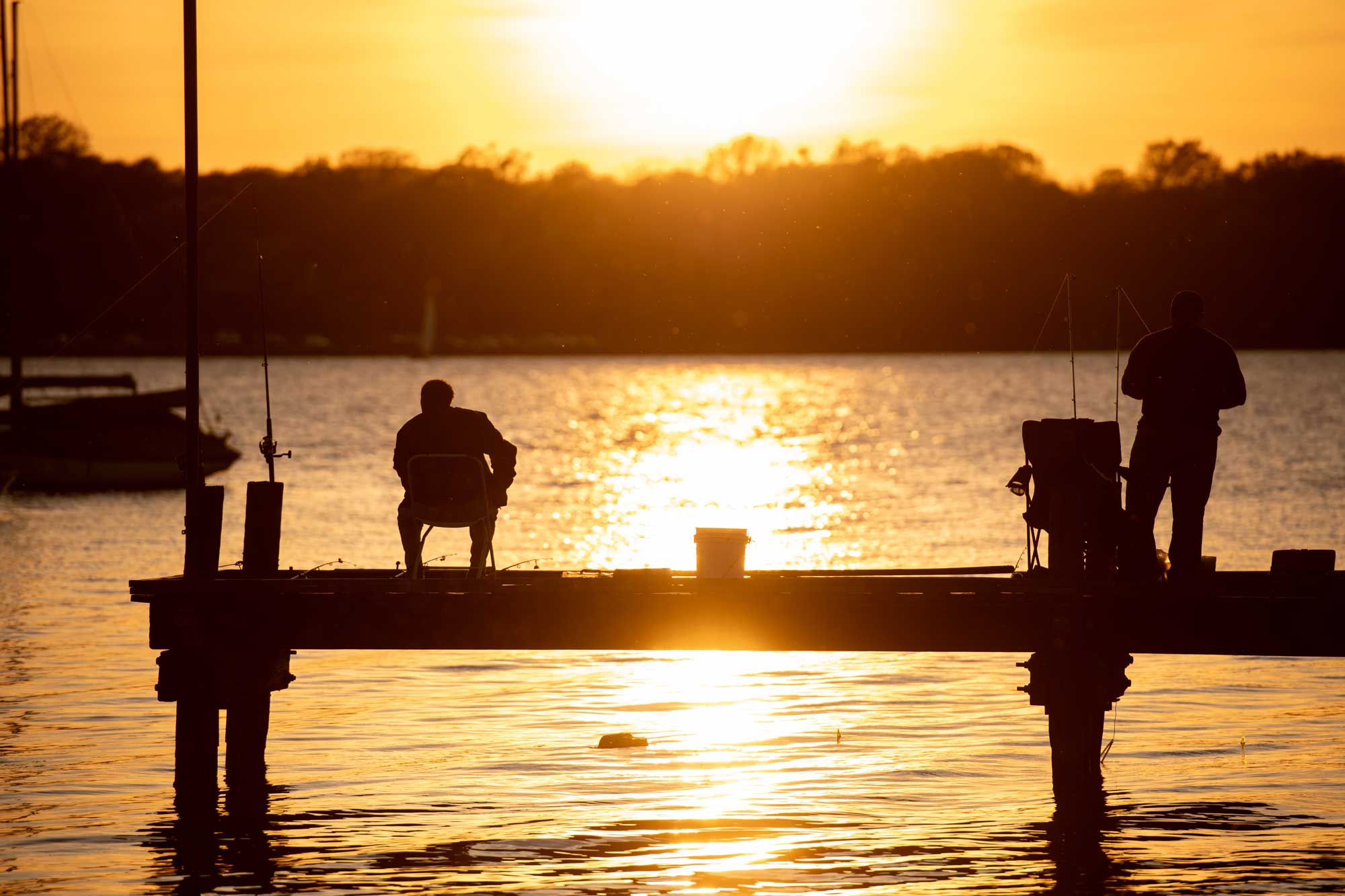 silhouette-of-people-fishing-off-of-a-dock-or-pier-during-sunset-golden-hour-or-sunrise